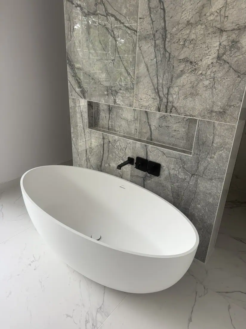 Freestanding bath against a marble-effect feature wall